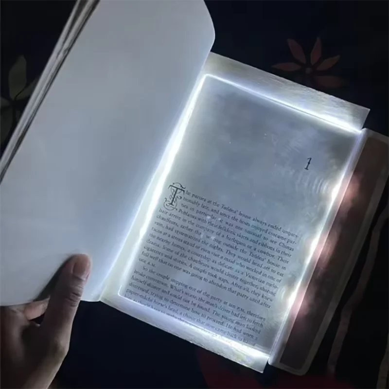 Open book with a light illuminating the text, held by a hand.