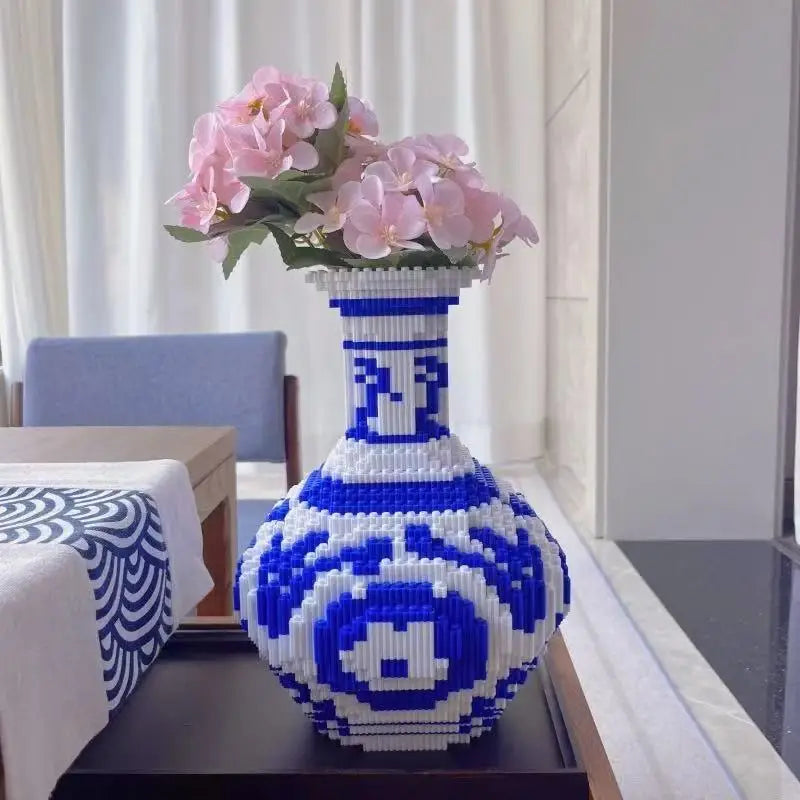 Blue and white patterned building block puzzle vase used for decor and housing pink flowers on a table; transforming games and STEM puzzles to household decoration.