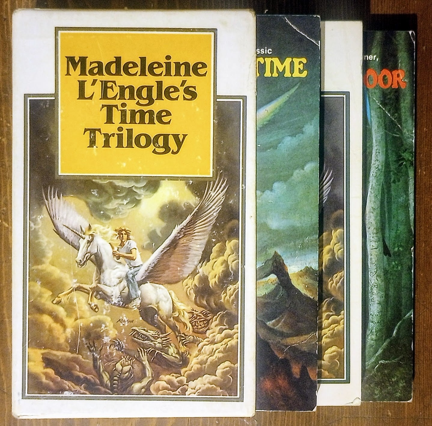 Book cover of 'Madeleine L'Engle's Time Trilogy' with a winged horse illustration on a wooden surface.