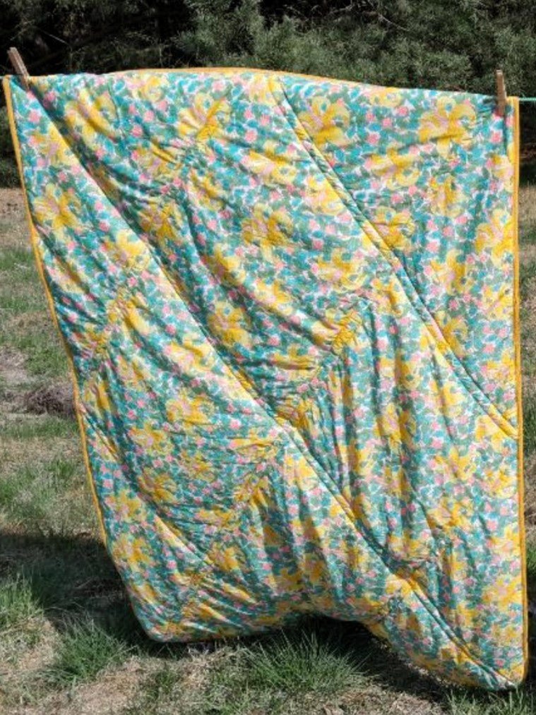 Liberty Fabric Blanket by 'House Without Borders' displayed hanging on a clothesline outdoors.