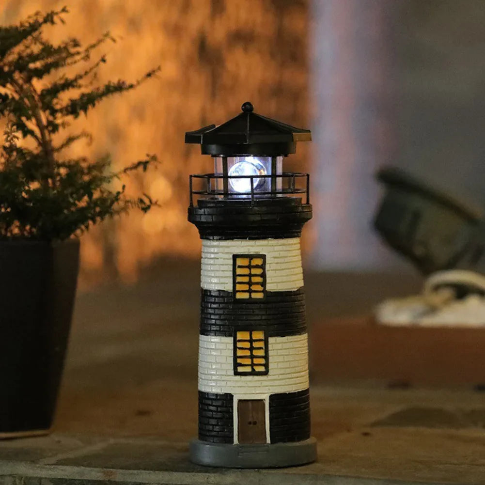 Model lighthouse with a light on, placed indoors with a plant and blurred background