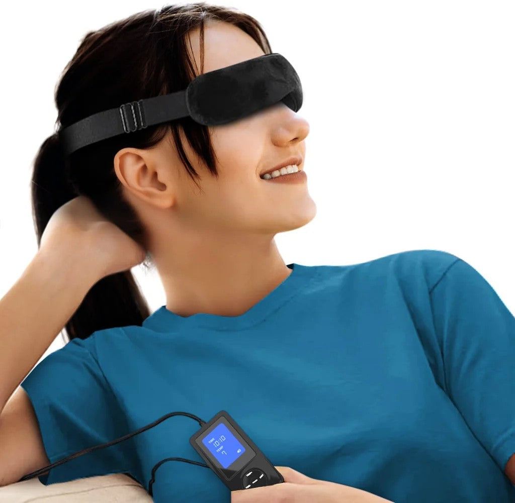 Woman wearing a black sleep mask with a handheld electronic device on a white background