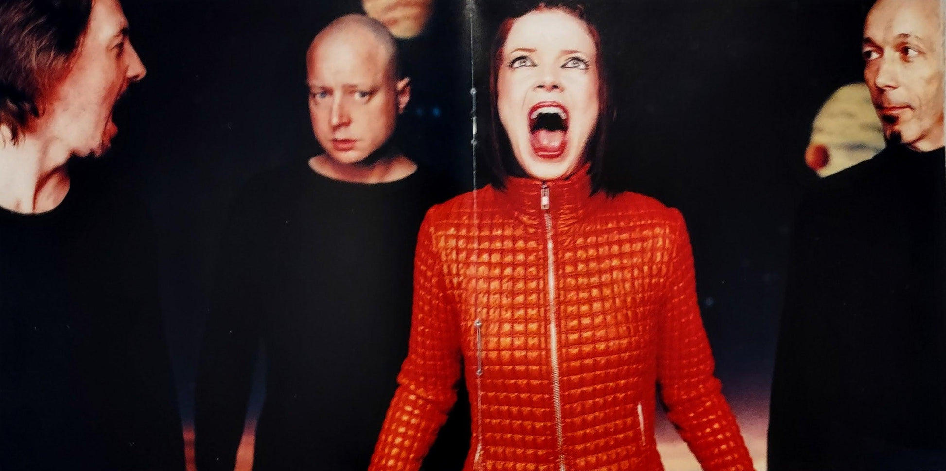 Shirley Manson in a red textured outfit with other people from the band Garbage in the background