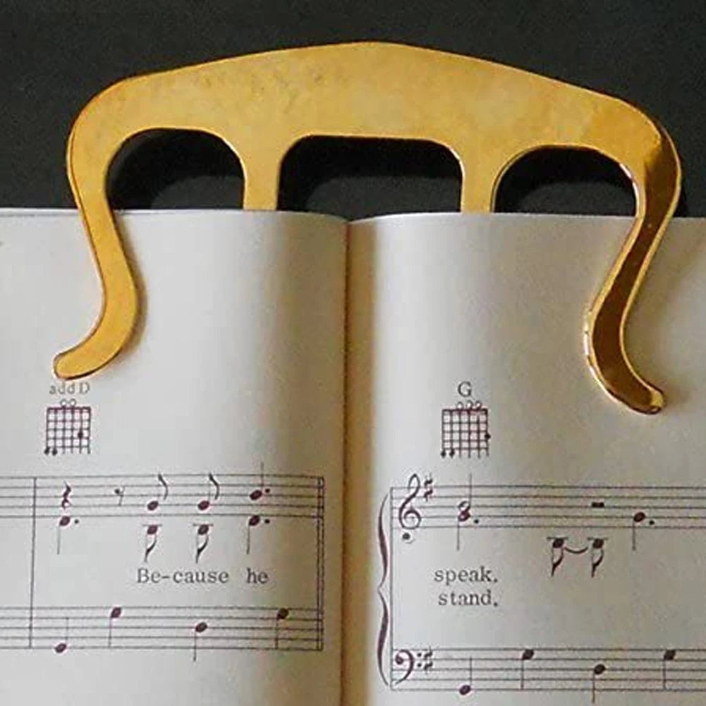 Gold guitar capo on an open book with music notes