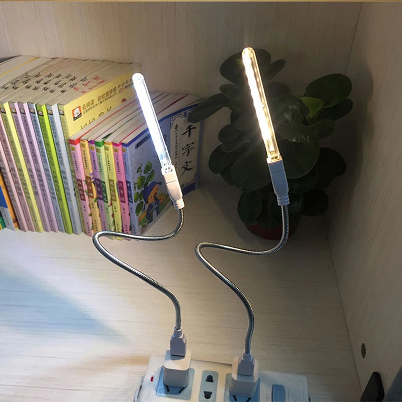 Flexible LED lamp on a desk with books and a plant in the background