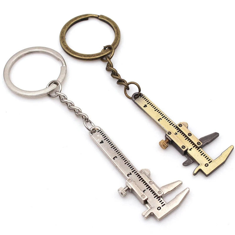 Two caliper-shaped keychains, one silver and one gold, on a white background.