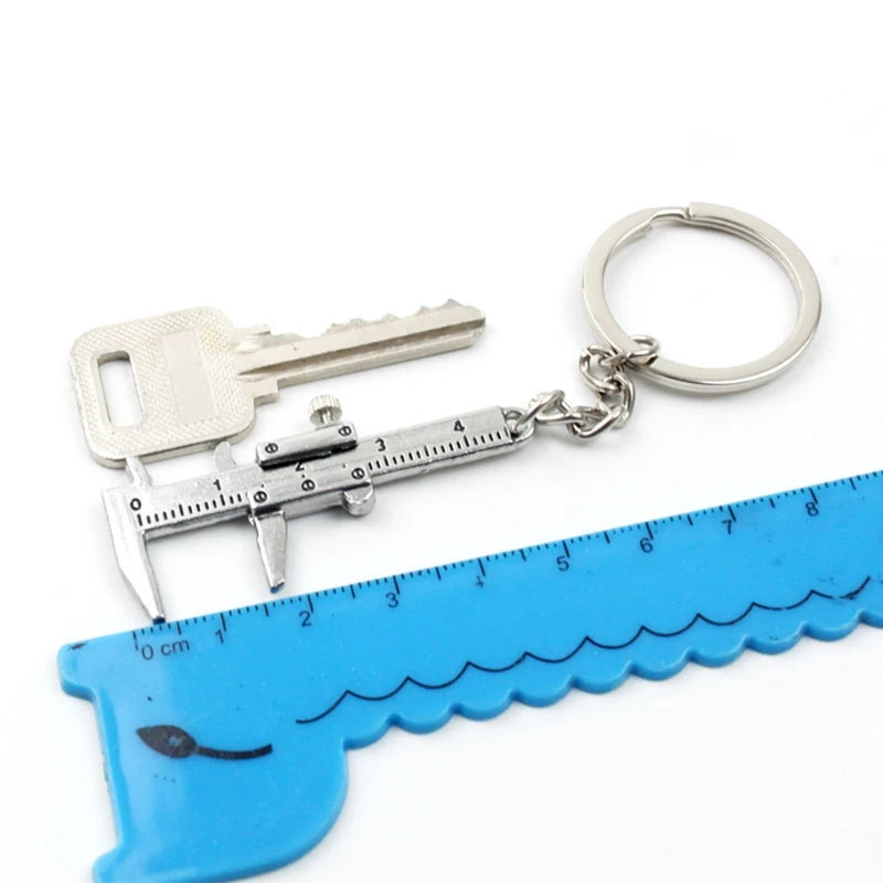 Keychain with blue shark-shaped ruler, metal caliper, and key on a white background