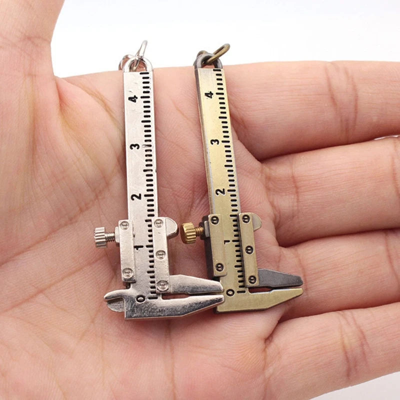 Two miniature caliper earrings held in a hand