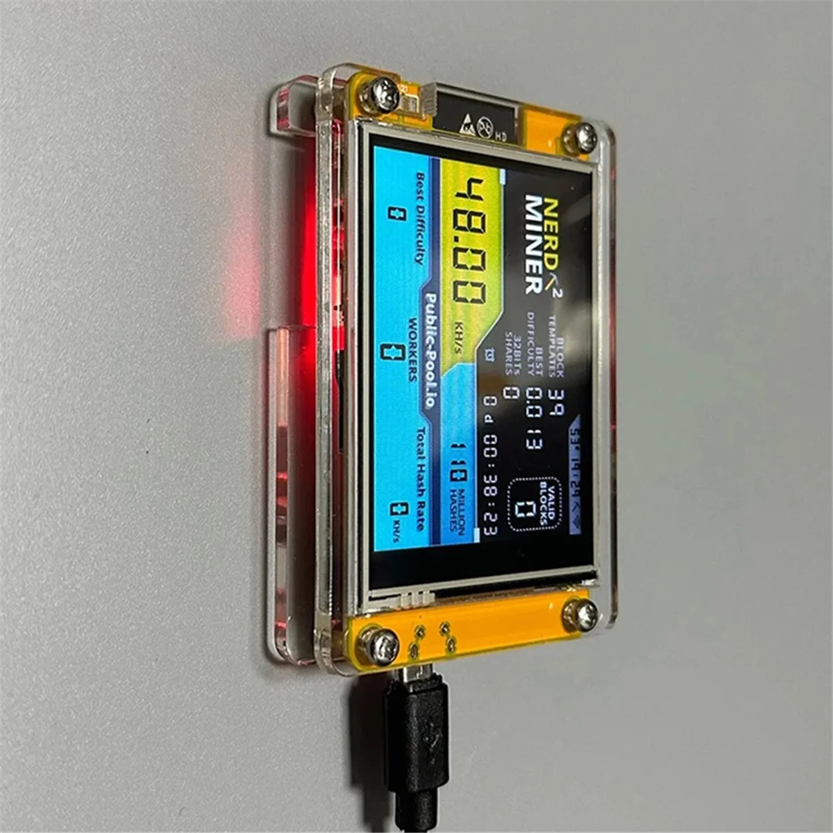 NerdMiner v2 device with activated digital display mining on a grey background.