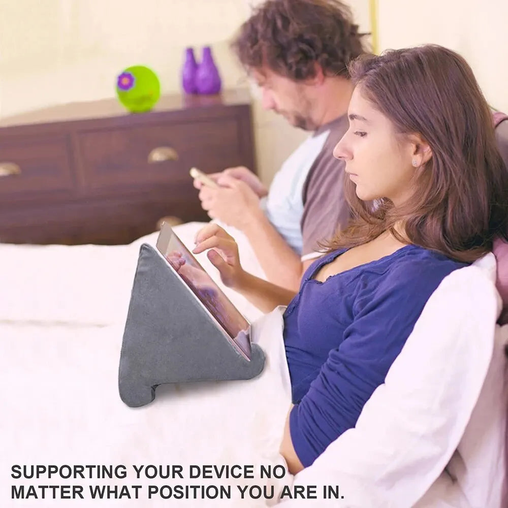 Woman using a tablet on a pillow stand while sitting on a bed with a man.