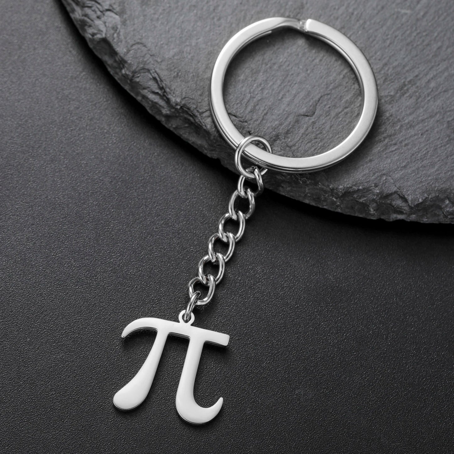 Silver keychain with pi symbol on a dark stone surface