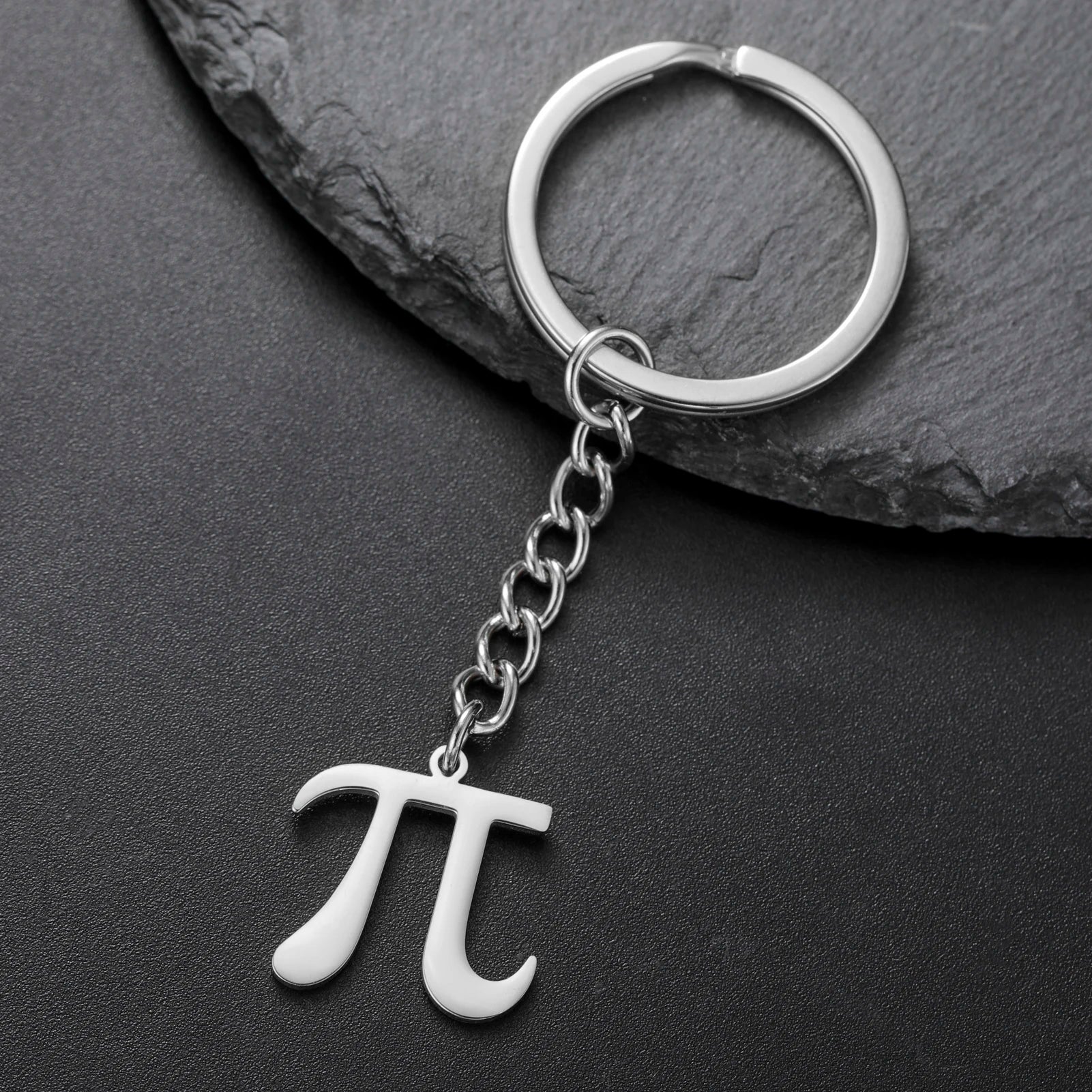 Silver keychain with pi symbol on a dark stone surface