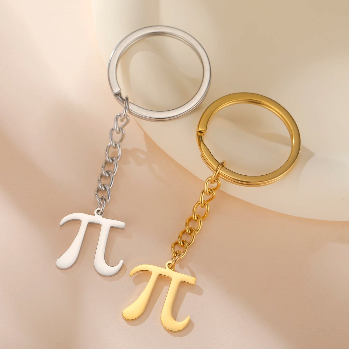 Two keychains with pi symbols, one silver and one gold, on a beige background.