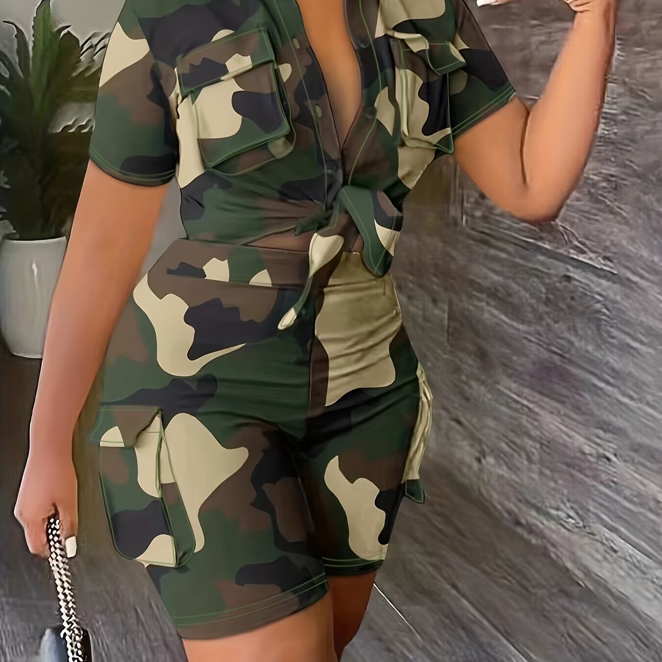 Curvy woman wearing a camouflage outfit with a purse, posing indoors.