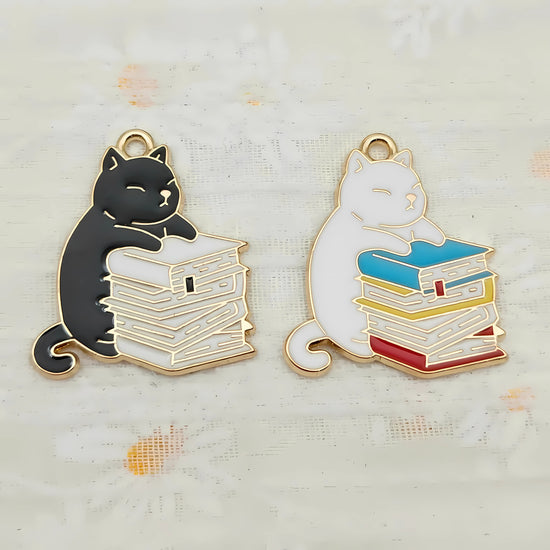 Necklace pendants showing a husky cat hugging a stack of books charm. Options are black cat and white books and white cat with multi-colored books.