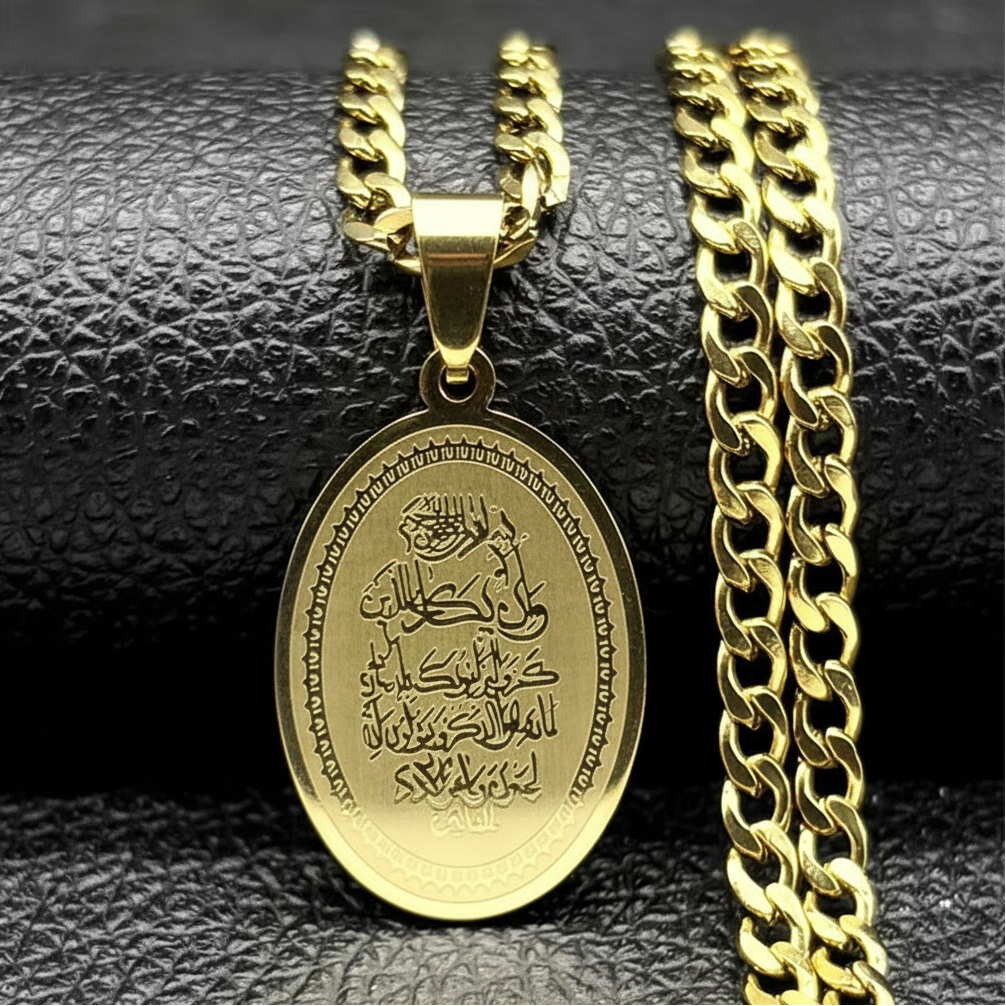 A gold-colored stainless steel pendant necklace with a chain, featuring an oval pendant with a Quranic verse inscription.