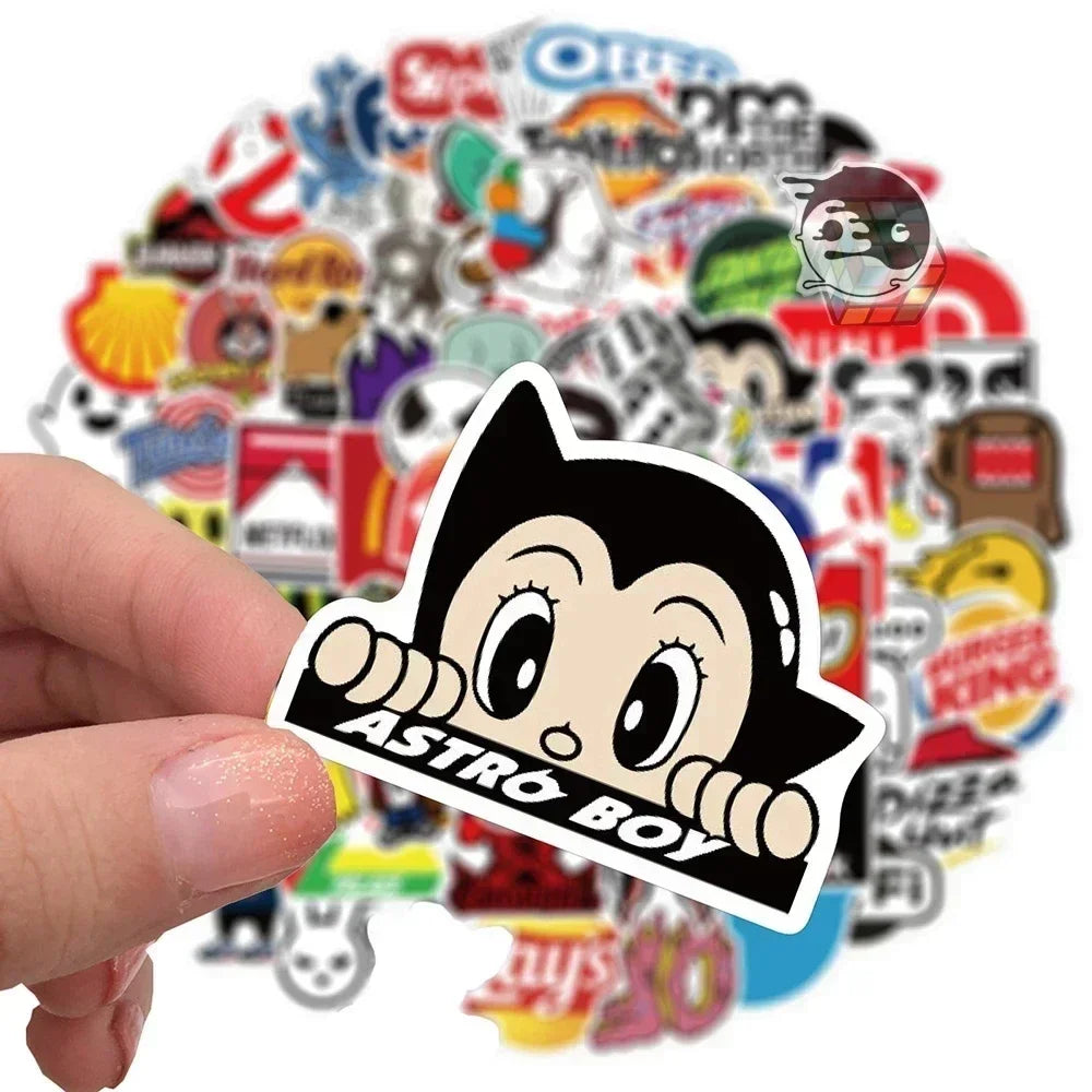 Hand holding a 'Astro Boy' sticker with various other stickers in the background