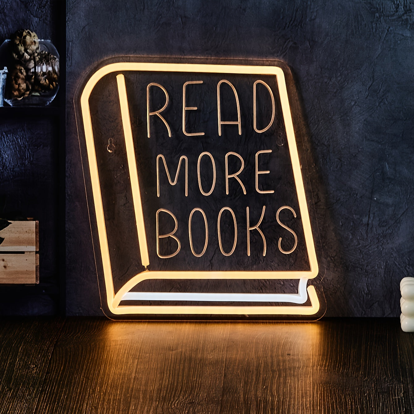 Neon sign shaped like a book with 'Read More Books' text on a dark background