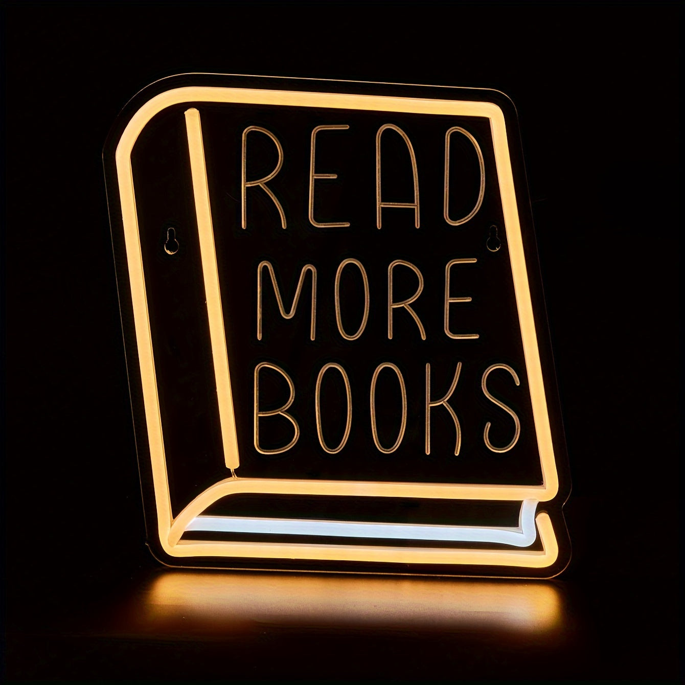 Neon sign shaped like a book with 'Read More Books' text on a black background