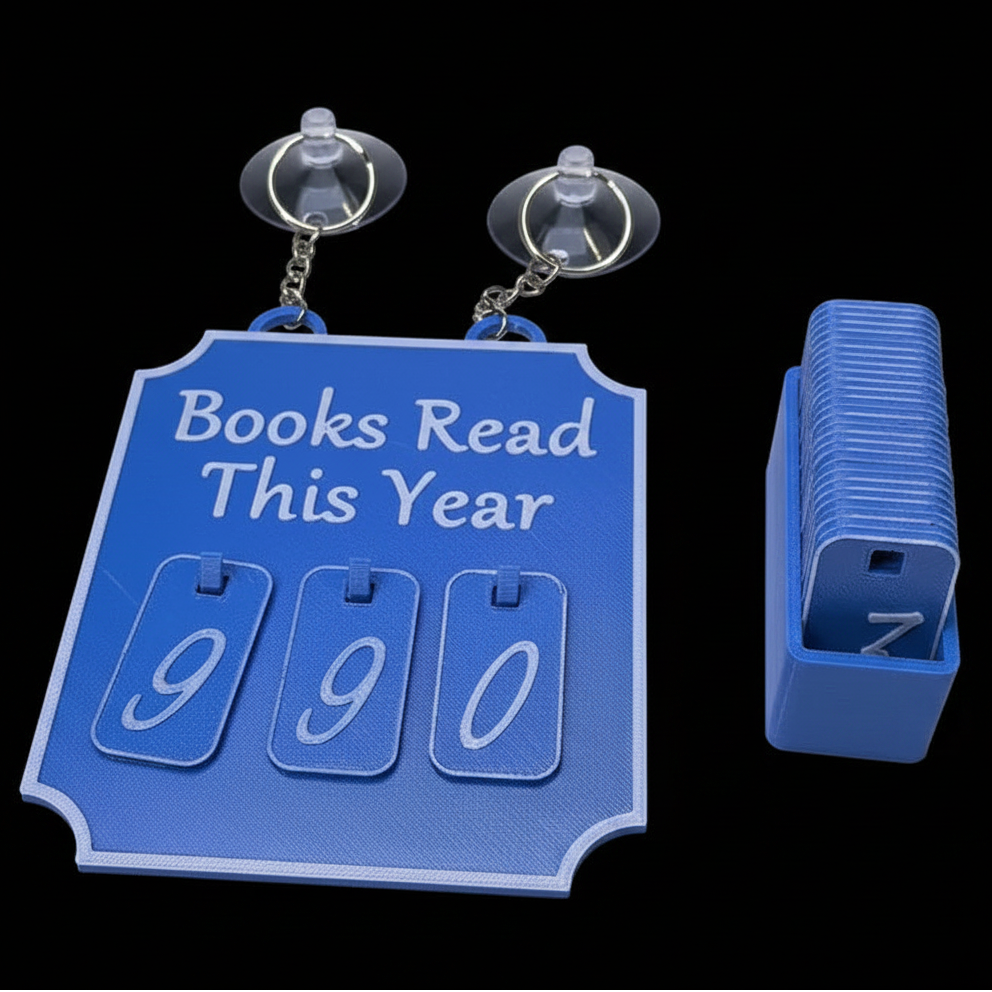 A blue flip-book style calendar titled 'Books Read This Year' with three large flip pages showing '990', shown with its matching blue storage box on a black background.
