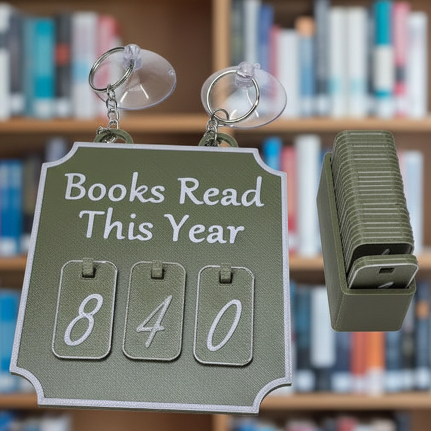 A wall-mounted flip calendar bookshelf sign hanging from two clear suction cups, with the sign reading 'Books Read This Year' and three flip pages showing 840. A stack of matching calendar-like page  number markers for the marque shown to the right, against a blurred library background.