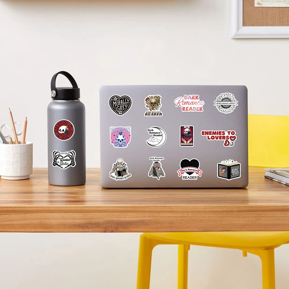 Laptop with various dark academia romance stickers on a desk next to a water bottle