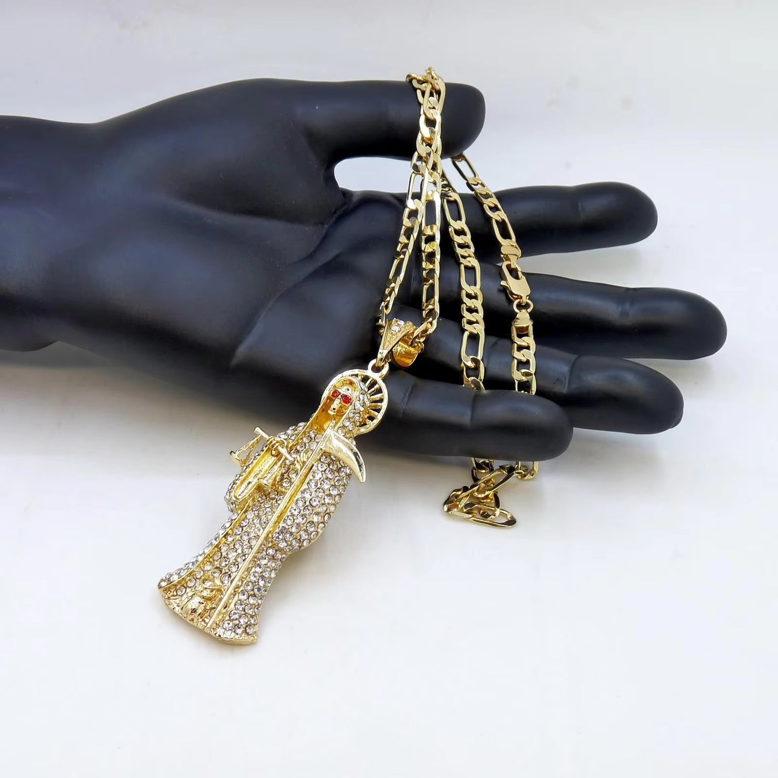 Santa Muerte necklace with white stone pendant and figaro chain style necklace being displayed draped over a mannequin hand and white background.
