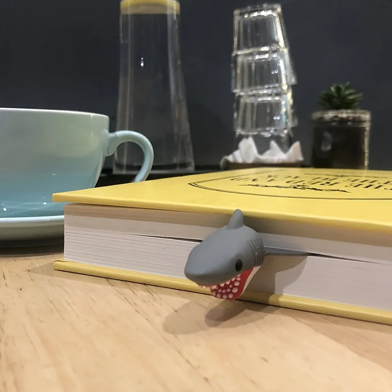 Shark-shaped bookend on a yellow book with a cup and glasses in the background