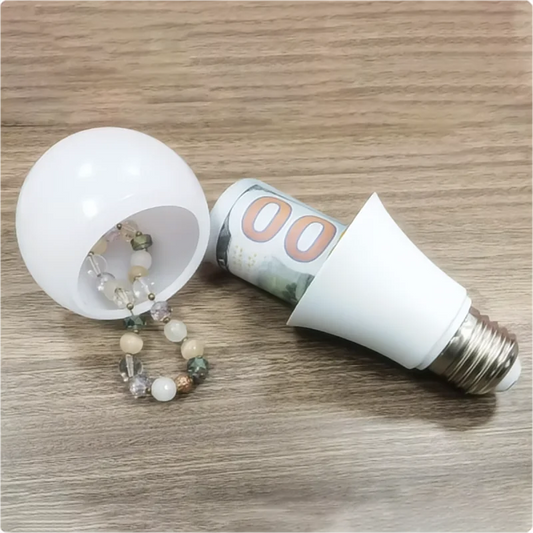 Light bulb-shaped container secret storage space with beads and a rolled-up bill on a wooden surface.