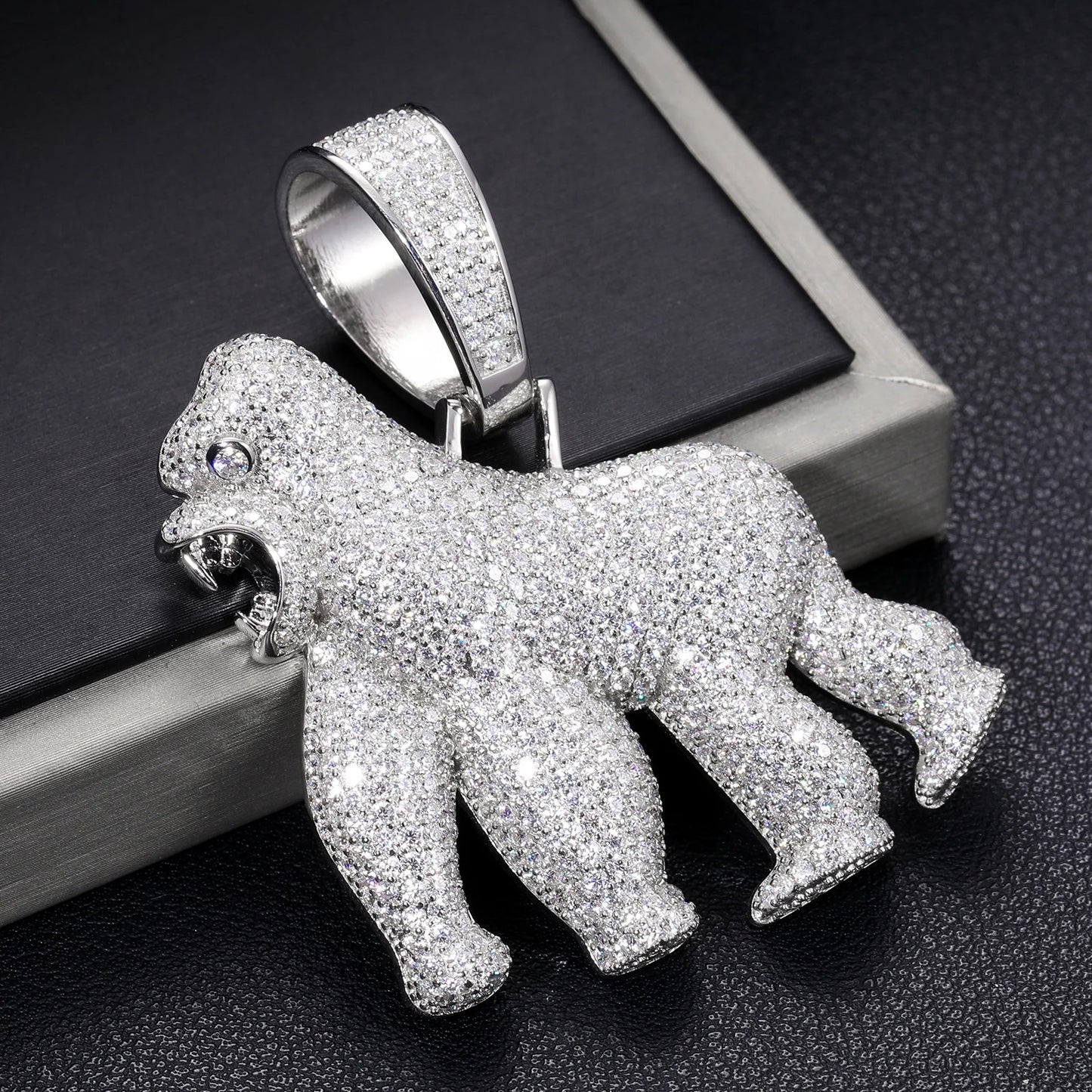 Silver gorilla pendant with gemstones on a dark textured surface