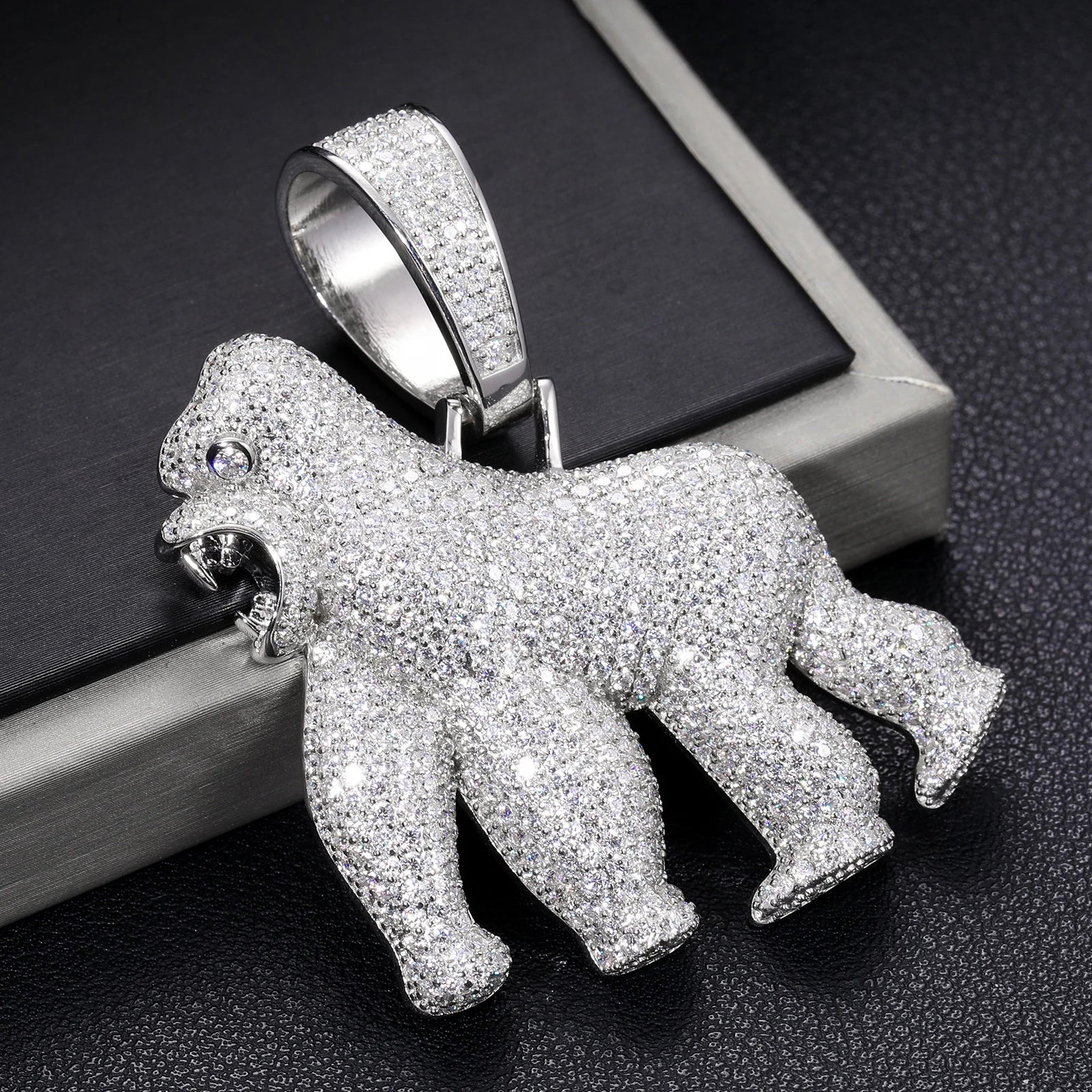 Silver gorilla pendant with gemstones on a dark textured surface