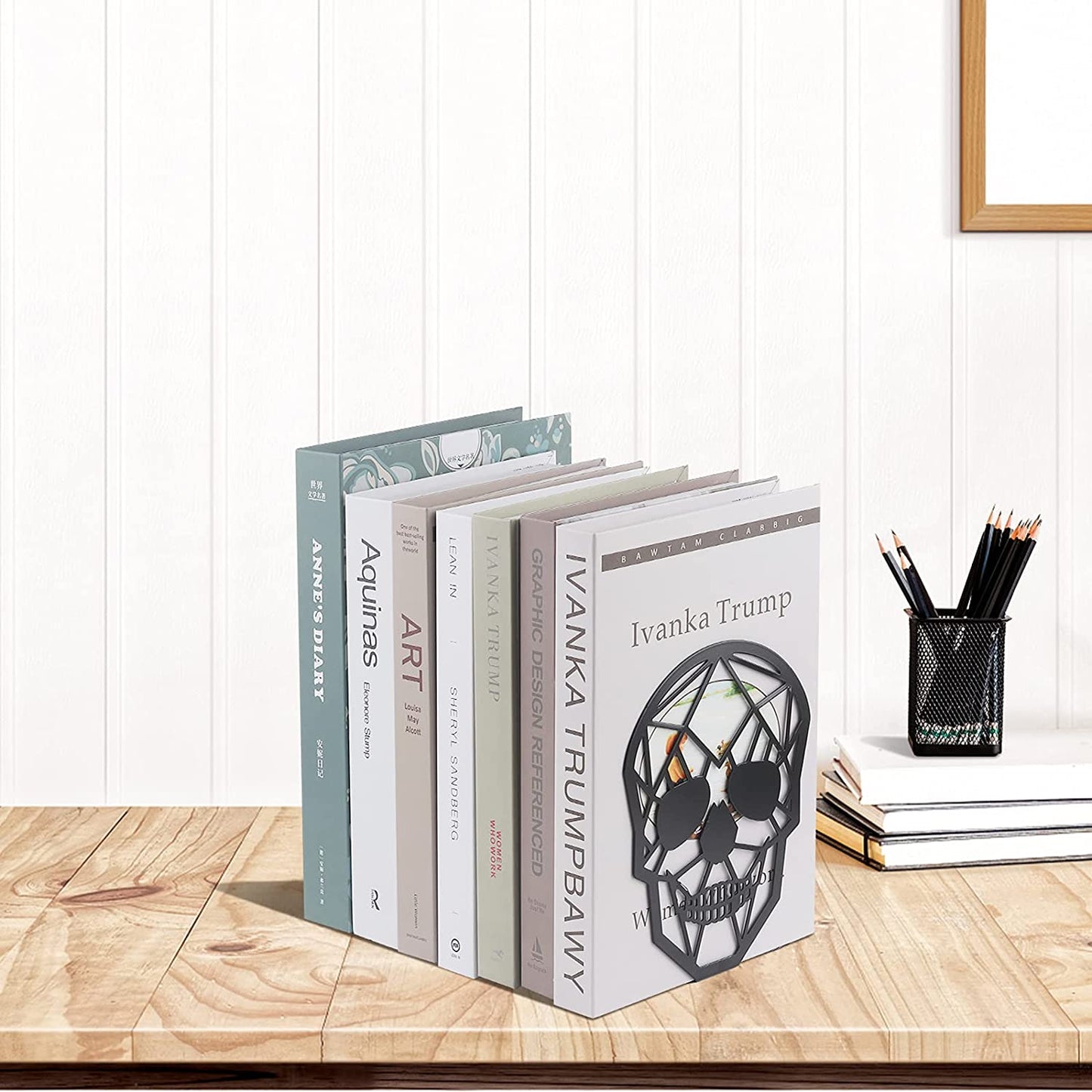 Skull bookends holding up book collection on desk next to other desk and home office supplies.