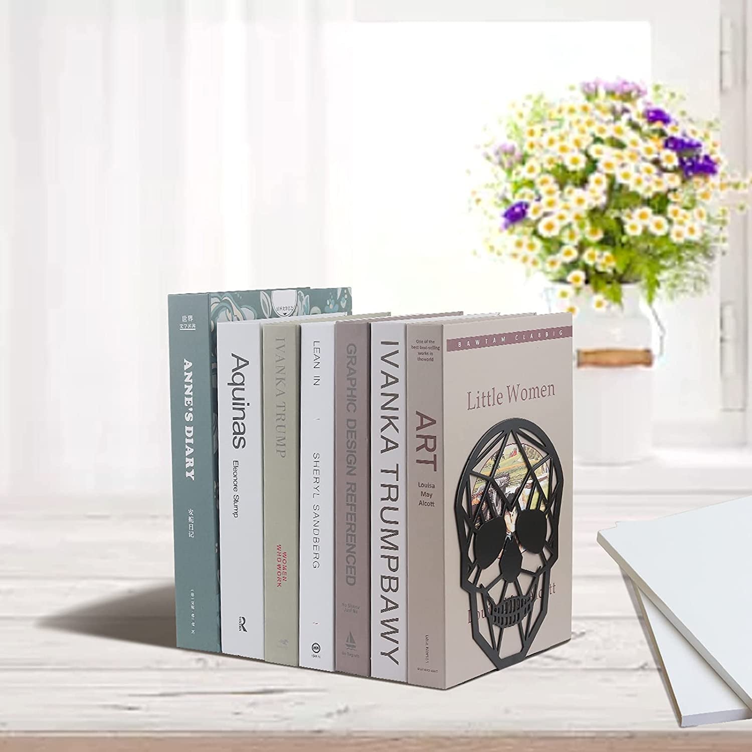 Skull metal bookends holding up book set on desk.