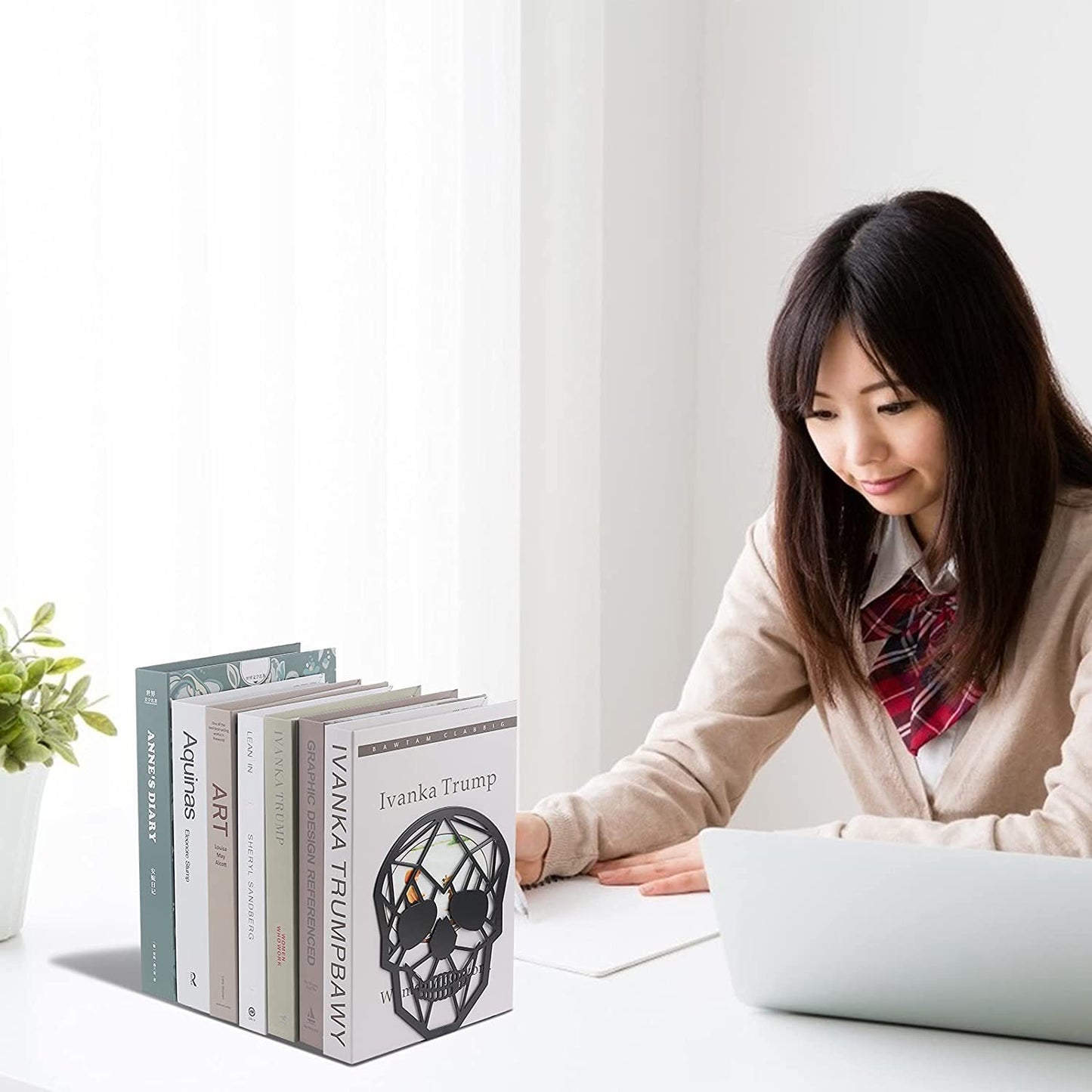 Skull bookends on desk supporting book collection with student working at desk.