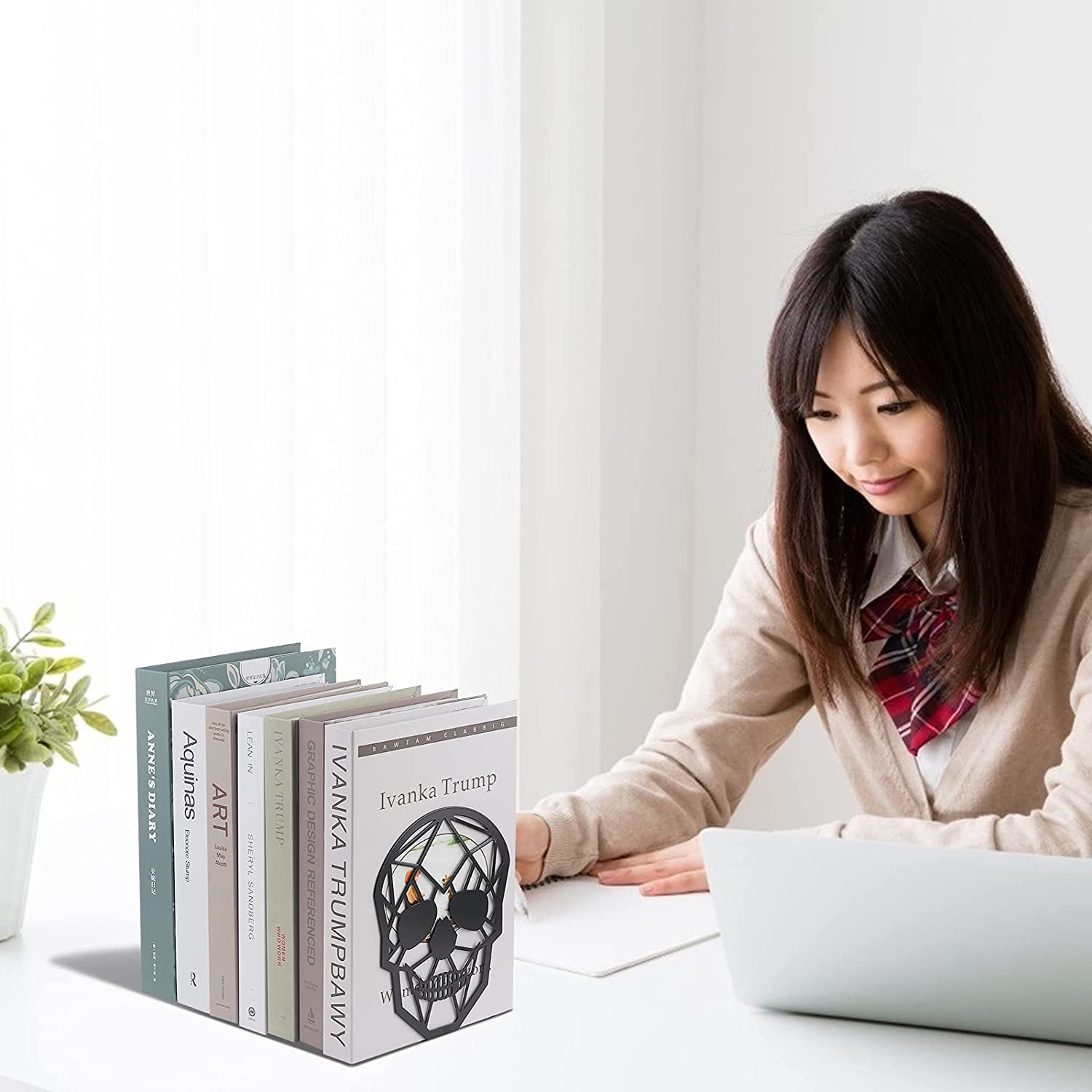 Skull bookends on desk supporting book collection with student working at desk.
