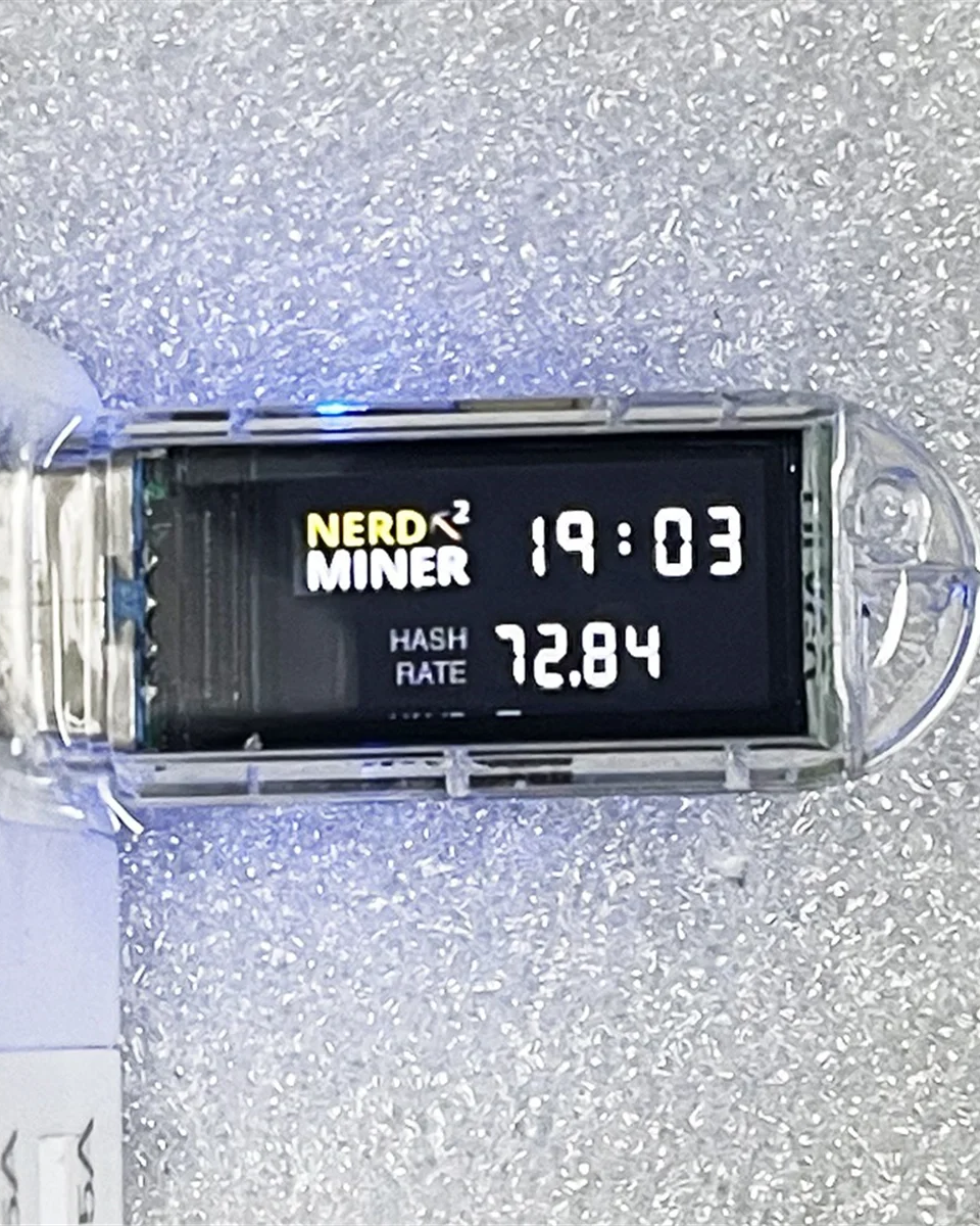 Digital display showing 'NERD MINER' and hash rate on a glittery background