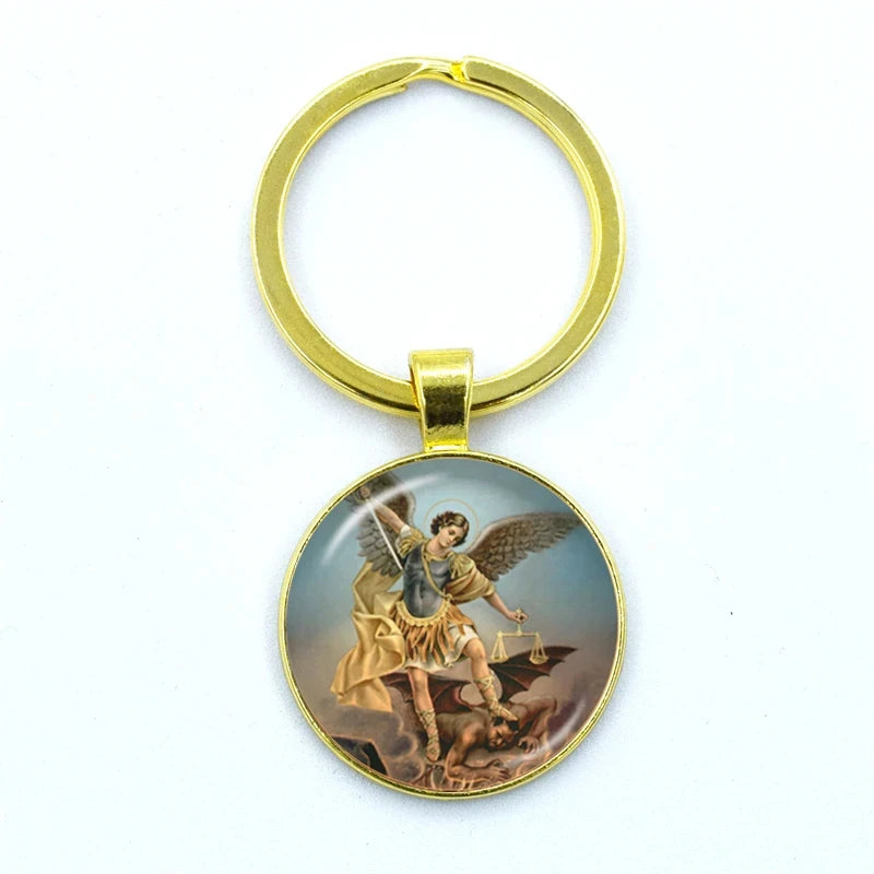 Gold keychain with an angelic figure michael and the scales of justice design on a white background