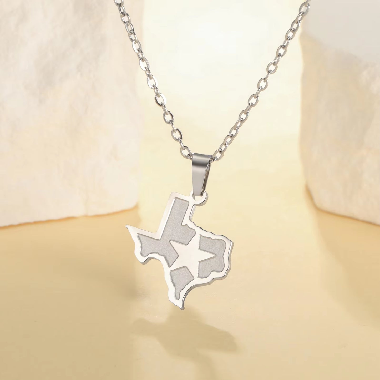 State of Texas necklace pendant with lone star over Texas and link chain in silver, featured draped over a stand on display and bright background.