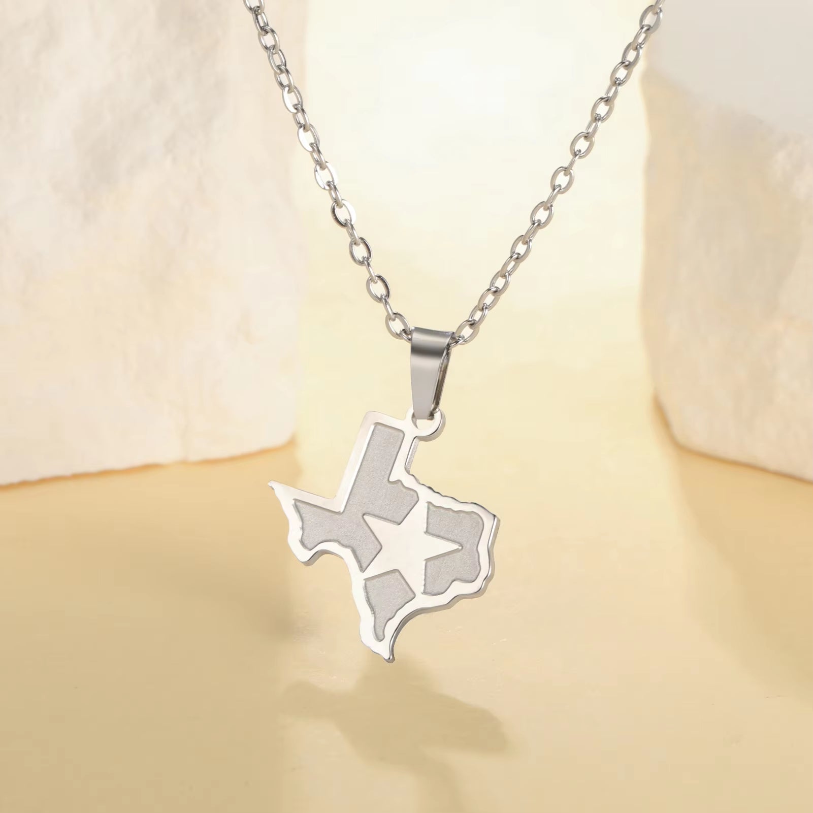 State of Texas necklace pendant with lone star over Texas and link chain in silver, featured draped over a stand on display and bright background.