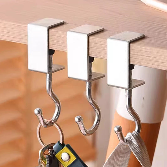 Three metal hooks attached to a wooden surface with keys and a towel hanging from them.