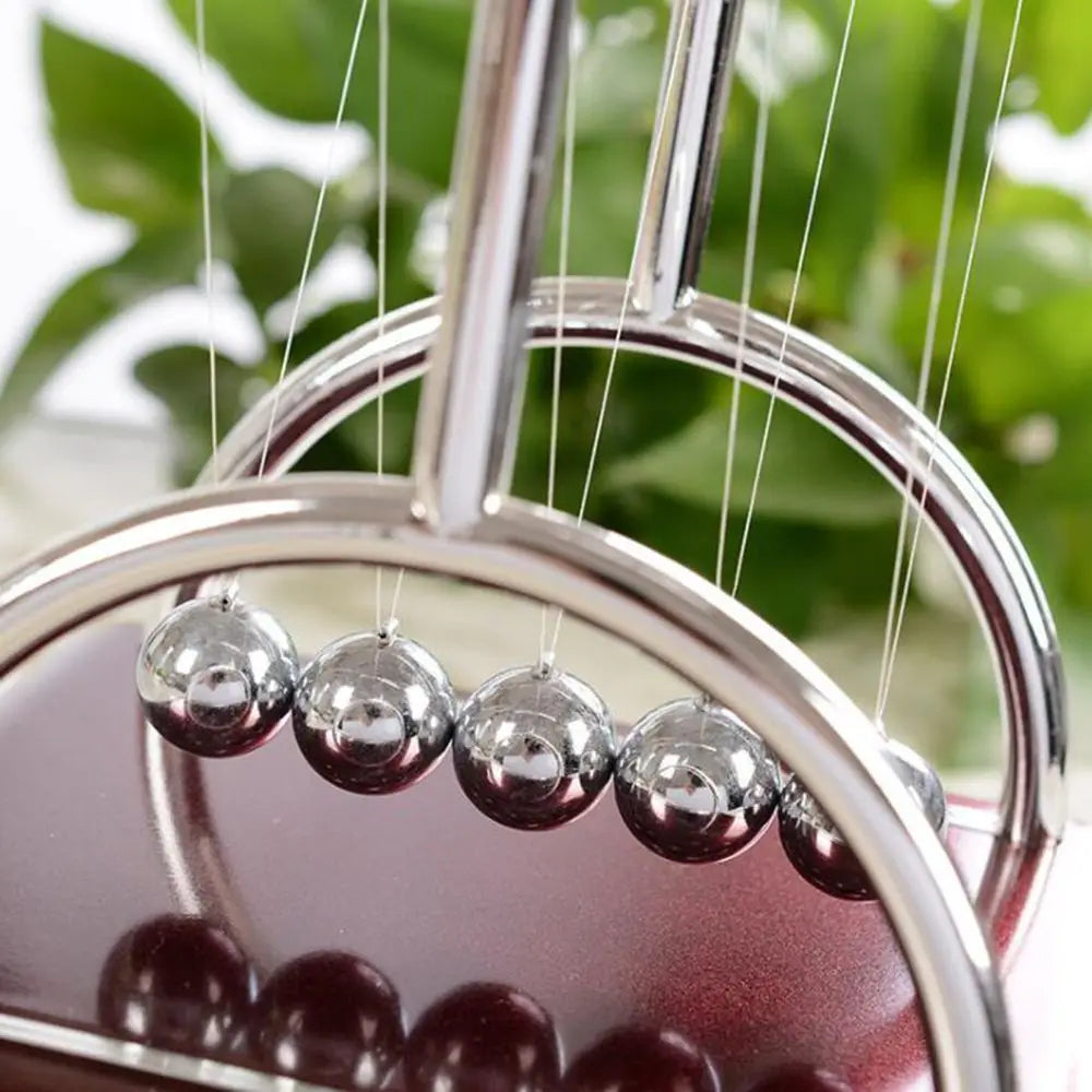 close up of Arch style 'Table Newton Pendulum | Terrific Scientific Desk-Decoration' in motion to showcase quality of materials and elegance of design.
