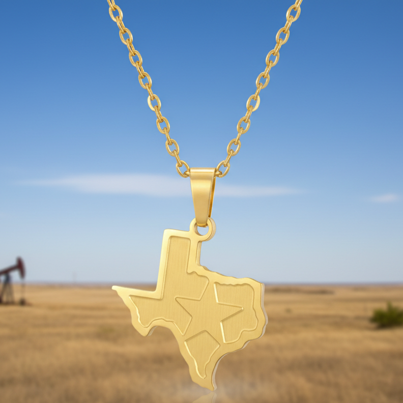 A gold pendant necklace shaped like the state of Texas with a star cutout, hanging from a gold chain against a blurred outdoor background of blue sky and dry grass.