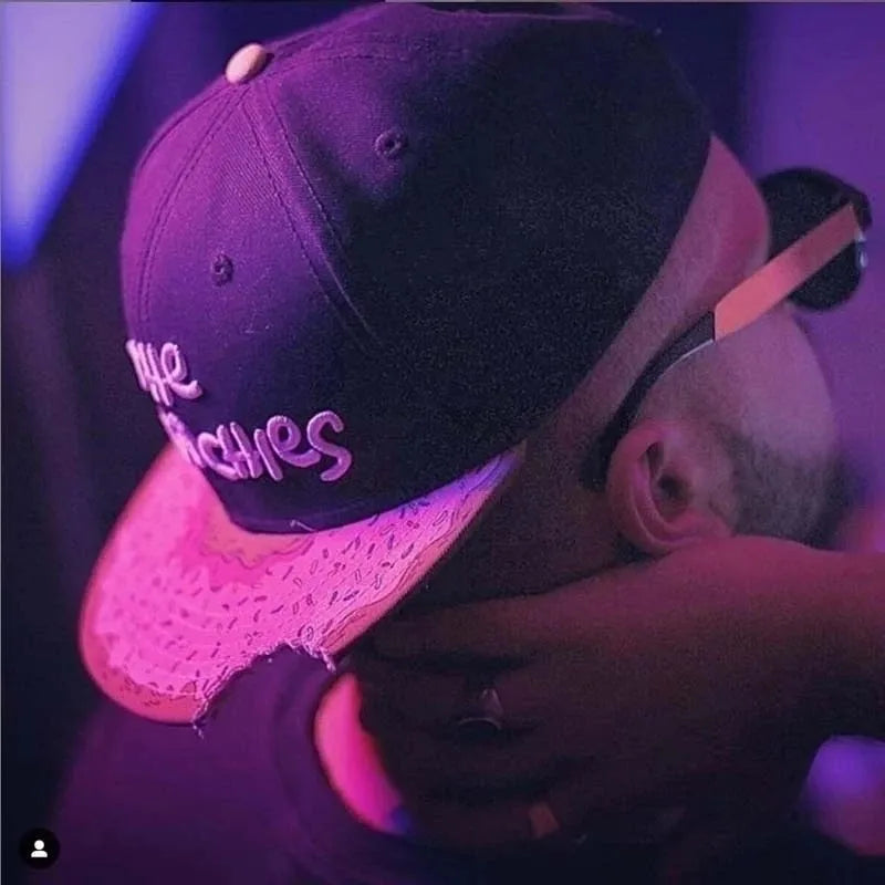 Model rocking The Munchies snapback hat with pink sprinkle donut brim and black crown turned backwards.