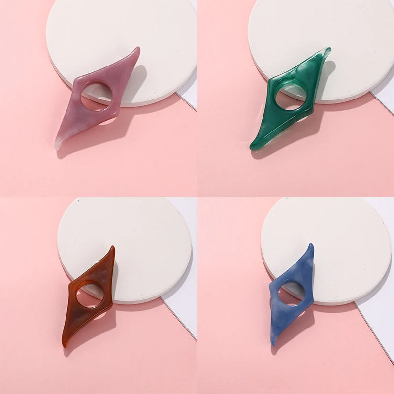 Collection of resin thumb bookmark page holders in assorted marbled colors (pink, blue, green, amber) resting on an open book.