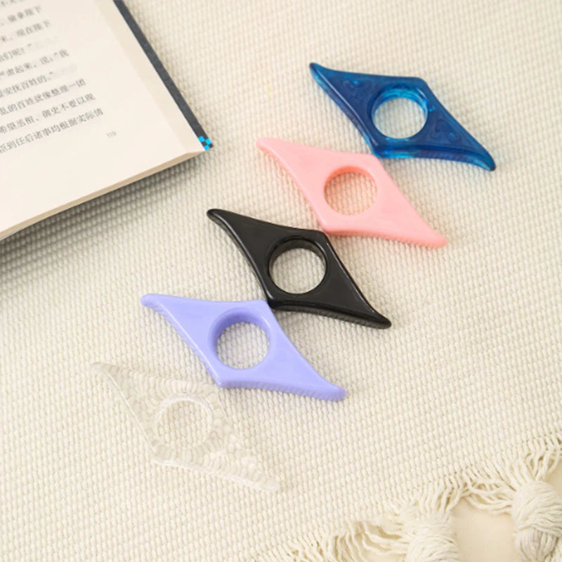 Collection of resin thumb bookmark page holders in assorted marbled colors (pink, blue, green, amber) resting on an open book.