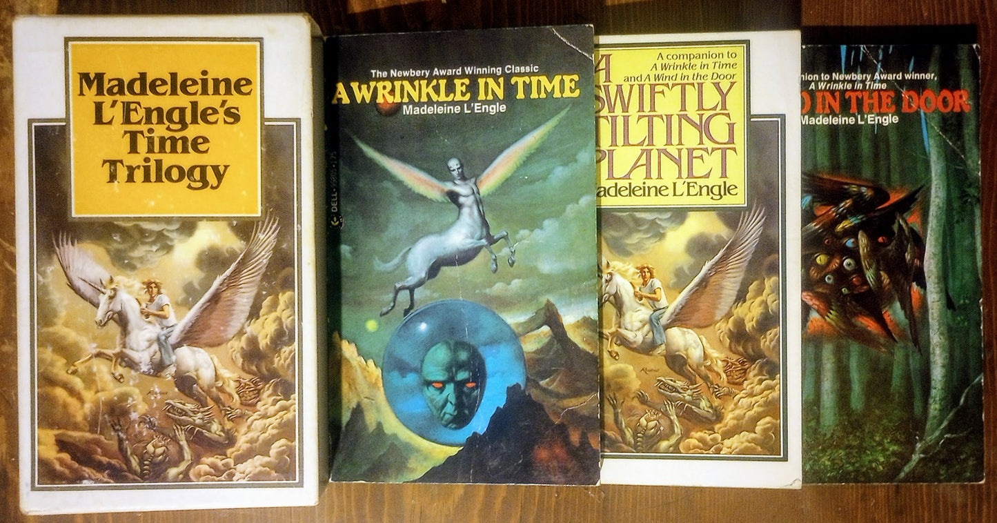 Three books from Madeleine L'Engle's 'Time Trilogy' next to the case cover art on a wooden surface.