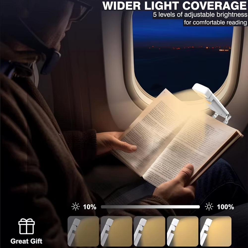 Person sitting in airplane window seat at night using clip-on travel book light attached to book and reading.