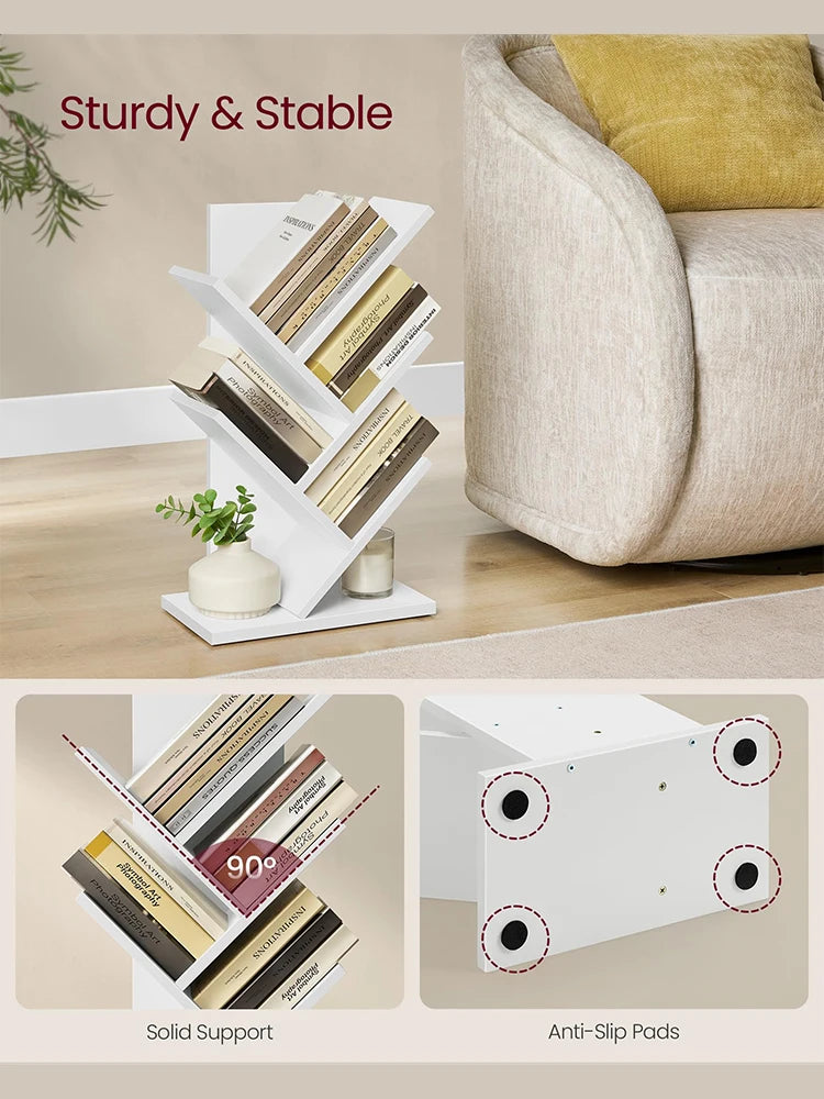 White bookshelf with books and decorative items on a wooden surface, with a couch in the background.