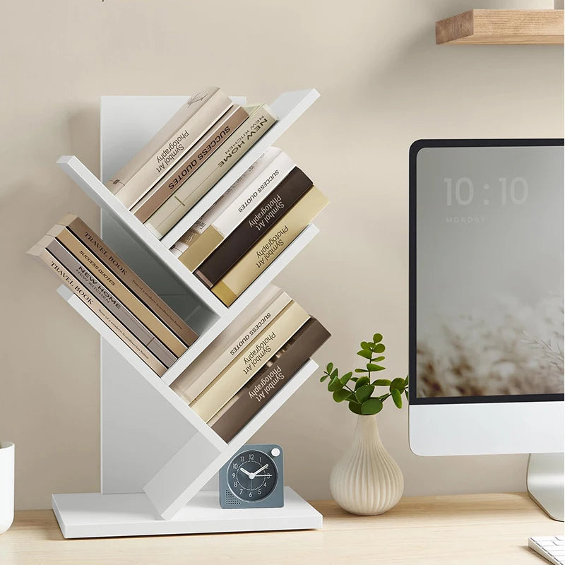 White tree-shaped bookshelf with books on a desk next to a computer monitor.