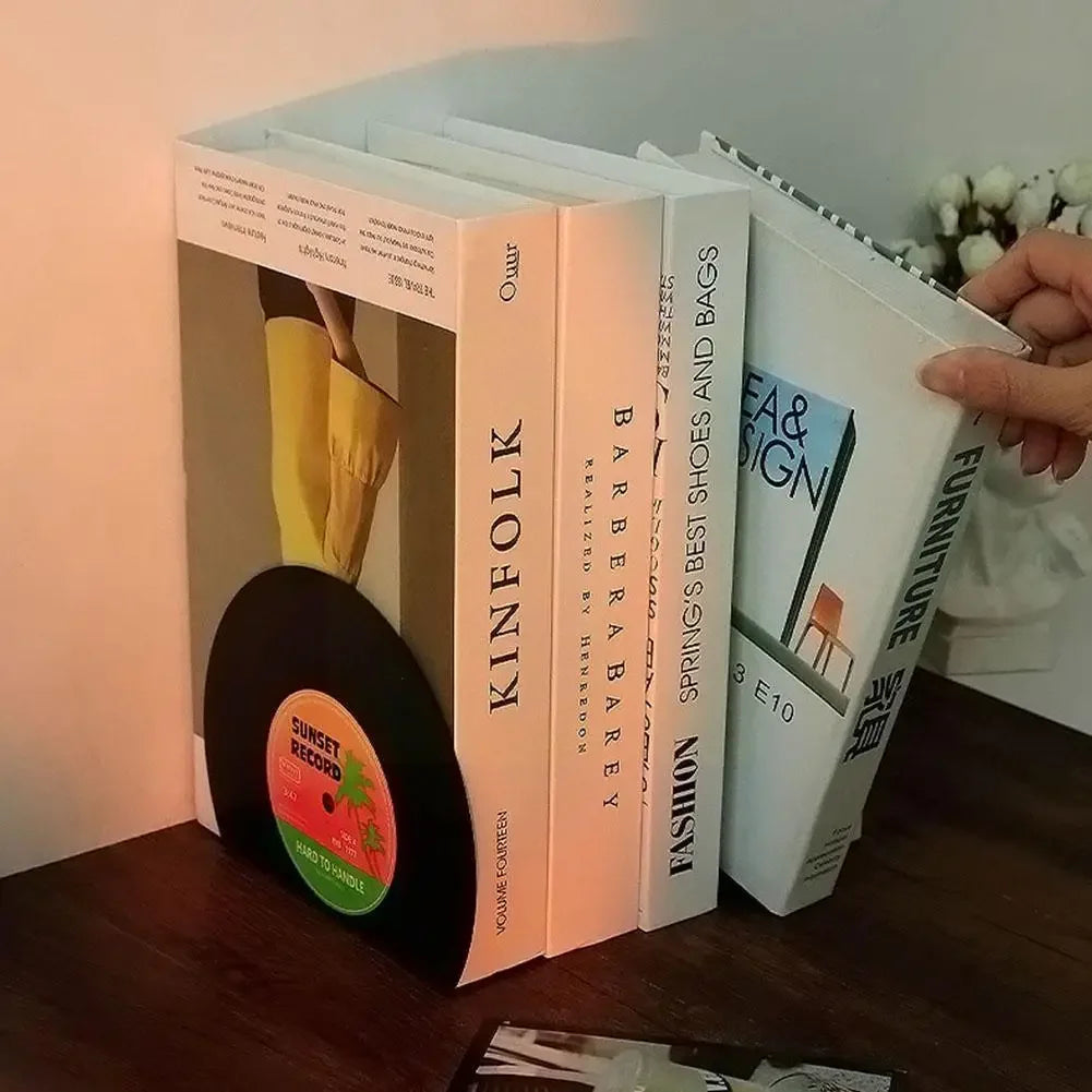 Stack of books with a vinyl record and a hand holding one of the books.